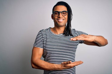 Sarışın, çizgili tişörtlü, gözlüklü, kocaman ve büyük beden işareti olan genç, Afro-Amerikan bir adam. Kameraya bakıp gülümsüyor. Ölçüm konsepti.