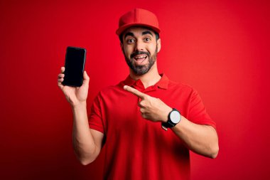 Sakallı, akıllı telefonlu yakışıklı teslimatçı yemek uygulamasını el ve parmağıyla göstererek çok mutlu bir şekilde sunuyor.