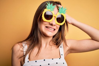 Sarı arka planda ananas güneş gözlüğü takan genç, güzel esmer kadın elleri başının üstünde, utanç ve şaşkınlık dolu, sinirli ve hayal kırıklığına uğramış bir halde. Hata için korku ve üzüntü.