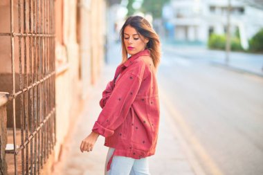 Kasabanın caddesinde duran kırmızı ceketli güzel bir kadın.