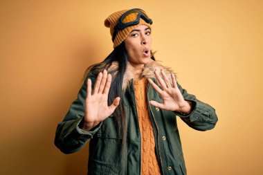 Kış havası için kayak gözlüğü ve palto takan genç, güzel bir İspanyol kadın. Avuçlarını kaldırıyor, reddediyor ve iğrenç bir ifadeyle reddediyor. Dur ve yasakla.