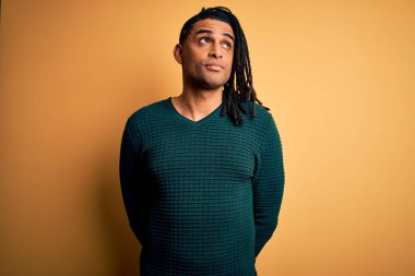 Genç, yakışıklı, Afro-Amerikan Afrikalı, rastalı yeşil kazak giyen, gülümseyen ve kafasını çeviren..