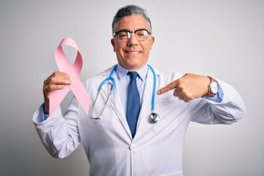 Orta yaşlı, yakışıklı, gri saçlı, elinde pembe kanser kurdelesi olan, kendini işaret eden bir doktor.