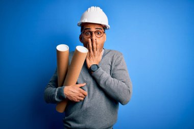 Genç Afro-Amerikan Afro-Amerikan mimar elinde güvenlik kaskı, elinde mavi parmak izleri, ağzı kapalı, utancından ağzı açık, korkunun ifadesi, sessizlikten korkan, gizli bir konsept