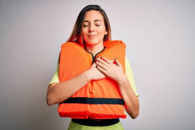 Mavi gözlü, beyaz arka planda turuncu can yeleği giyen, elleri göğsünde, gözleri kapalı ve yüzünde minnet ifadesi olan genç, güzel sarışın bir kadın. Sağlık kavramı.