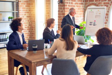 Bir grup iş adamı toplantıda mutlu ve kendinden emin gülümsüyor. Ofisteki pano ve çizelgeleri kullanarak birlikte sunuma bakıyoruz..