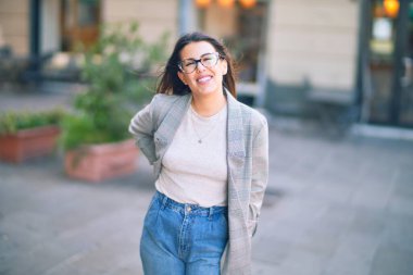 Mutlu ve kendinden emin gülümseyen genç ve güzel bir kadın. Kasaba caddesinde yüzünde gülümsemeyle dikilirken