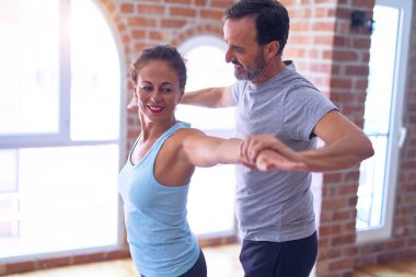 Orta yaşlı güzel sporcu çift mutlu gülümsüyor. Yoga dersinden sonra spor salonunda durup esneme hareketleri yapmak.