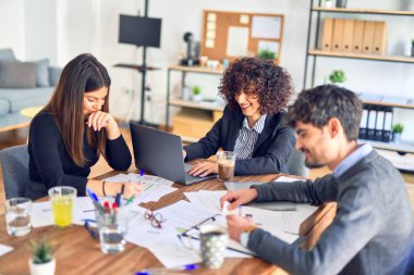 Bir grup iş adamı mutlu ve kendinden emin gülümsüyor. Yüzünde gülümsemeyle çalışmak, dizüstü bilgisayar kullanmak ve ofiste konuşmak.