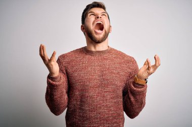 Sarışın, sakallı ve mavi gözlü genç adam beyaz arka plan üzerine gündelik süveter giyiyor deli deli deli bağırıyor ve agresif bir ifade ve kollarla bağırıyor. Hayal kırıklığı konsepti.