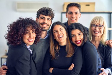 Bir grup iş adamı mutlu ve kendinden emin gülümsüyor. Ofisteki kameraya bakarak birlikte poz vermek.