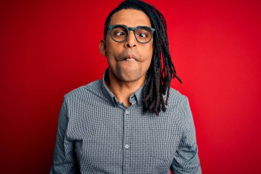 Rastgele gömlek giyen, gözlüklü, dudaklı balık suratlı, çılgın ve komik jestli genç, Afro-Amerikan bir adam. Komik ifade.