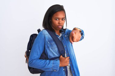 Afrika kökenli Amerikalı genç bir bayan sırt çantası takıyor. Arka planda, kameraya işaret ediyor. Ve sen, el işareti, ön taraftan pozitif ve kendinden emin bir hareket.