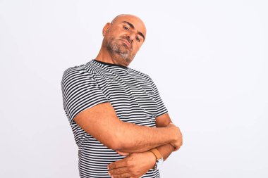 Orta yaşlı yakışıklı, çizgili donanma tişörtü giyen izole edilmiş beyaz arka planda kolları çapraz ve kendinden emin bir şekilde yan tarafa bakan bir adam.