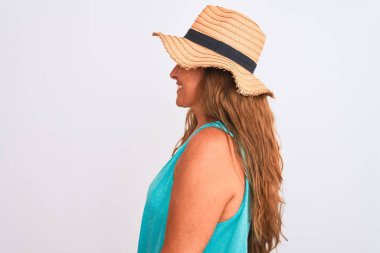 Orta yaşlı olgun bir kadın beyaz izole edilmiş arka planda yaz şapkası takıyor rahat bir görünüm takınıyor kendine güvenen bir gülümsemeyle doğal bir yüz ifadesi takınıyor..