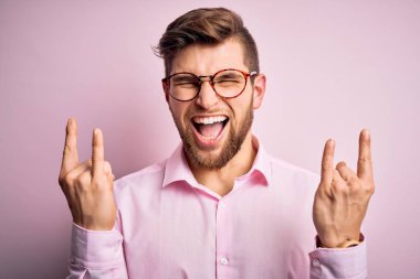 Sakallı, mavi gözlü, pembe tişörtlü ve gözlüklü çılgın bir ifadeyle bağıran yakışıklı sarışın adam elleri havada rock sembolü yapıyor. Müzik yıldızı. Ağır konsept.