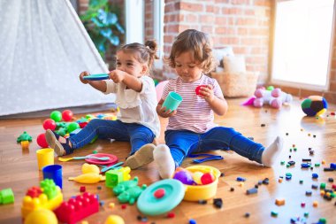 Anaokulunda plastik yemek ve çatal bıçak kullanarak yemek oynayan sevimli bebekler.