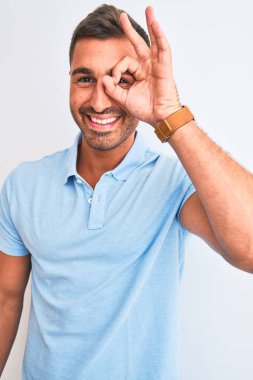 İzole edilmiş arka planda mavi tişört giyen, gülümseyen ve el pençe divan duran yakışıklı, zarif genç bir adam.