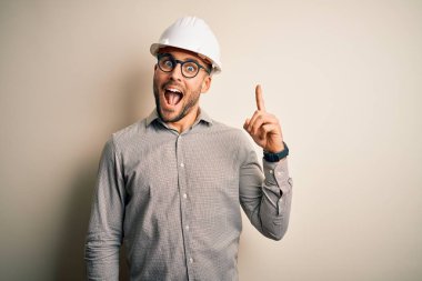 İzole edilmiş arka planda miğfer takan genç mimar başarılı bir fikir olduğunu işaret ediyor. Heyecanlı ve mutlu. Bir numara..