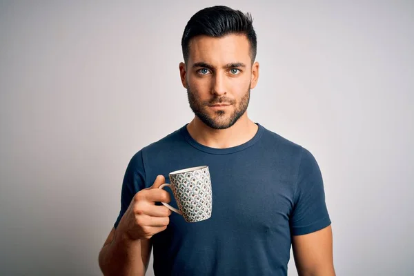 Young handsome man drinking a cup of hot coffee over white isolated background with a confident expression on smart face thinking serious