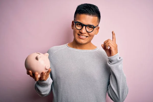 Jovem Bonito Latino Homem Segurando Porquinho Banco Sobre Isolado Fundo — Fotografia de Stock