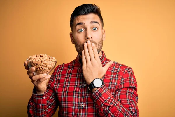 Joven Hombre Guapo Sosteniendo Tazón Con Cacahuetes Saludables Sobre Aislado — Foto de Stock