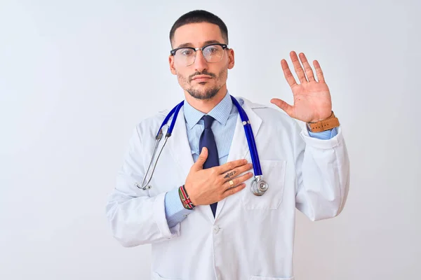 年轻的医生 戴着听诊器 背负孤立的背景 双手放在胸前 张开手掌 发誓效忠 — 图库照片
