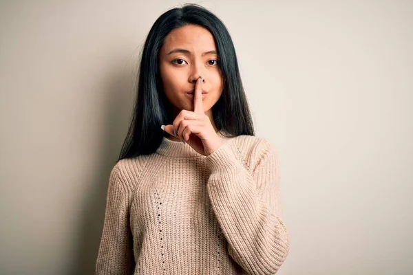 年轻美丽的中国女人穿着宽松的毛衣 披着孤立的白色背景 要求保持安静 手指放在嘴唇上 沉默和秘密概念 — 图库照片