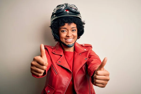 巻き毛を持つ若いアフリカ系アメリカ人のアフロバイクの女性は 手で肯定的なジェスチャーを行うことを承認オートバイのヘルメットを着て 親指を笑顔と成功のために幸せ 勝者のジェスチャー — ストック写真