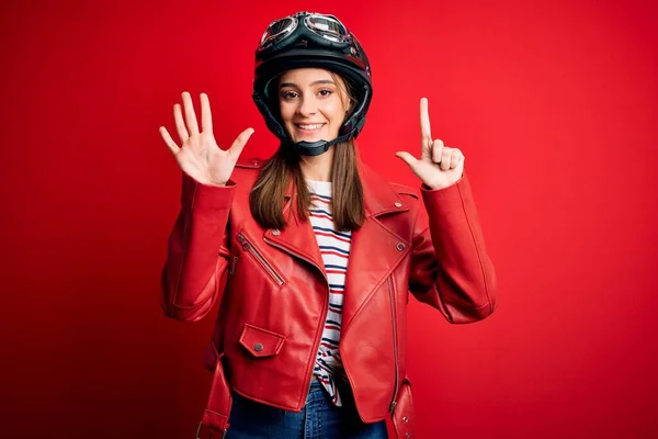若い美しいブルネット自転車ヘルメットと赤いジャケットを身に着けているオートバイの女性が表示され 指番号7で指摘しながら 自信と幸せ笑顔 — ストック写真