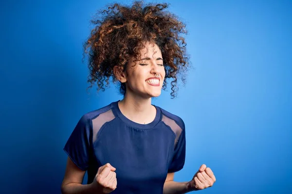 Młoda Piękna Kobieta Kręconymi Włosami Kolczykiem Luźnej Niebieskiej Koszulce Podekscytowana — Zdjęcie stockowe
