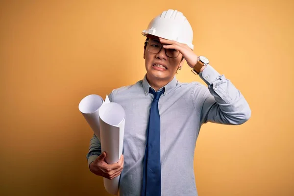 年轻英俊的中国建筑师头戴安全帽 头戴安全帽 头戴设计图 满脸羞愧和惊讶 愤怒和沮丧 恐惧和因错误而烦恼 — 图库照片