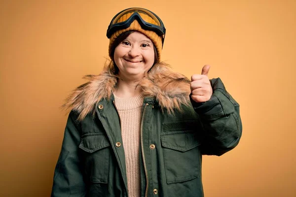 年轻的下意识的女人 穿着滑雪外套 戴着眼镜过冬 手举着快乐的大拇指做着快乐的手势 在镜头前看着成功的表情 — 图库照片
