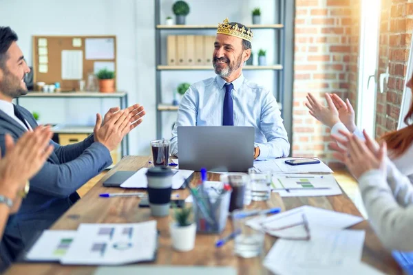 Group of business workers smiling happy and confident. Working together with smile on face applauding one of them wearing king crown at the office