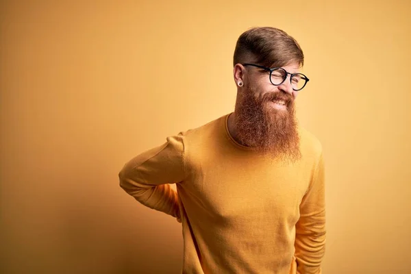 英俊的爱尔兰红头发男人 留着胡子 戴着眼镜 戴着黄色的隔离背景 用手触摸 肌肉疼痛 — 图库照片