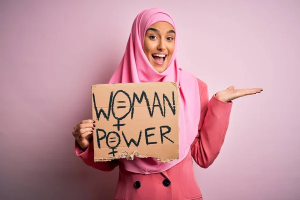 ピンクのイスラム教徒のヒジャーブを身に着けている若い活動家のアラブ女性パワーメッセージとバナーを保持非常に幸せと興奮 大きな笑顔で叫んで勝利を祝う勝者式と手を上げ — ストック写真