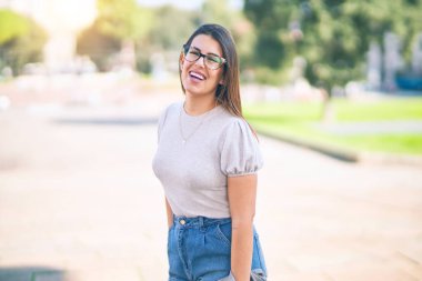 Mutlu ve kendinden emin gülümseyen genç ve güzel bir kadın. Kasaba caddesinde yüzünde gülümsemeyle dikilirken