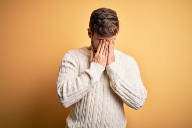 Sarışın, sakallı, mavi gözlü, sarı arka planda beyaz süveter giyen, yorgunluk ve baş ağrısı için gözlerini ovuşturan, uykulu ve yorgun yüzlü genç bir adam. Görüş sorunu