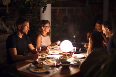 Güzel bir aile akşam yemeğinde terasta konuşuyor ve gülümsüyor