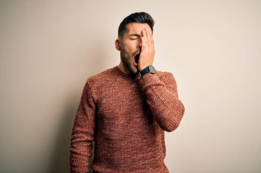İzole edilmiş beyaz arka plan üzerinde sıradan bir süveter giyen genç yakışıklı adam esnemekten yoruldu. Yüzün yarısını, gözünü ve ağzını eliyle kapattı. Yüzüm acıyor..