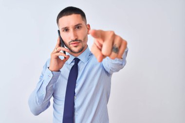 Genç yakışıklı iş adamı, izole edilmiş arka plan üzerinden arıyor. Kamerayı işaret ediyor ve sen, el işareti, ön taraftan pozitif ve kendinden emin bir hareket.
