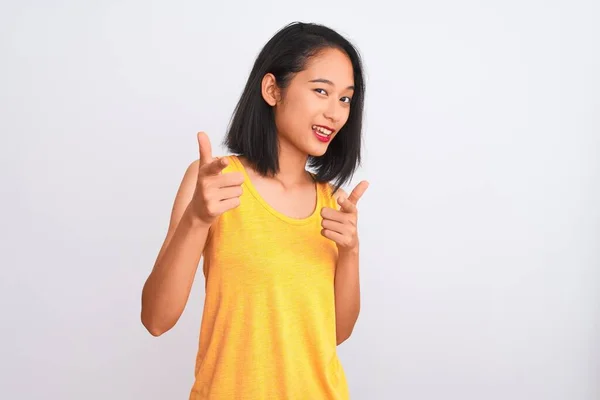 若い中国人女性が黄色のカジュアルなTシャツを着て 幸せと面白い顔を持つカメラに指を指して孤立した白い背景の上に立っている 良いエネルギーと振動 — ストック写真
