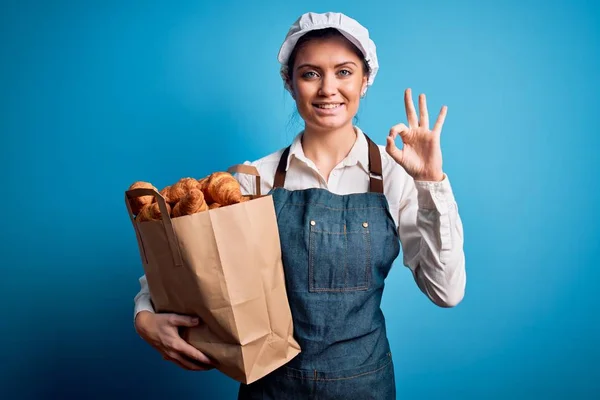 Mladá Krásná Pekařka Modrýma Očima Zástěře Drží Papírový Sáček Croissanty — Stock fotografie