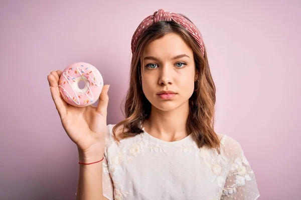 若いですブロンド女の子食べる甘いですベーカリーシュガードーナツ上のピンク隔離された背景とともに自信を持って式上のスマート顔考え深刻な — ストック写真