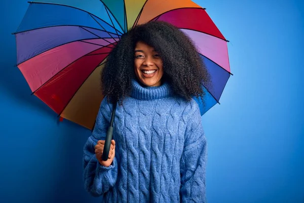 冬の天気の雨のためのカラフルな傘の下でアフロ髪の若いアフリカ系アメリカ人女性が立って 歯を示す自信を持って笑顔で笑顔で — ストック写真