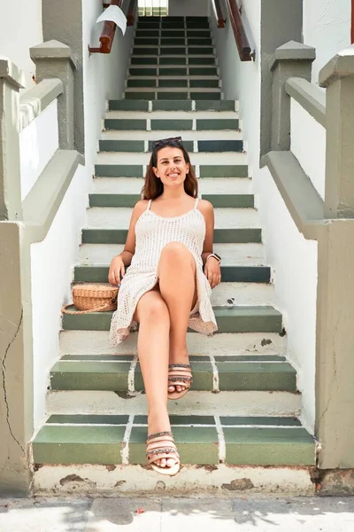 Young beautiful woman at the colorful village of Puerto de Mogan, smiling happy sitting on stairs on summer holidays