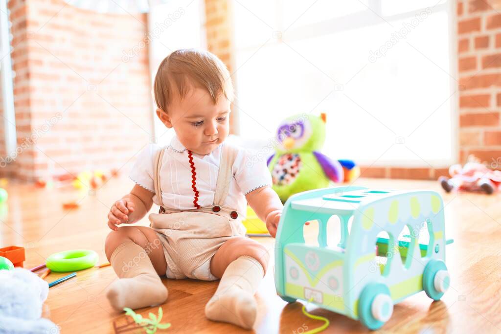 Adorable toddler playing around lots of toys at kindergarten