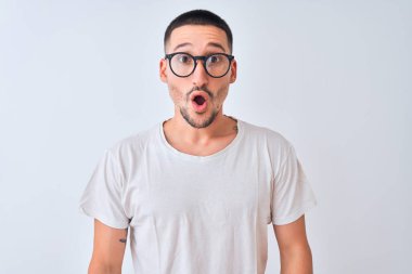 Gözlüklü genç yakışıklı bir adam, izole edilmiş arka planda duruyor. Şaşırmış ve korkmuş bir ifade, korku ve heyecanlı bir yüz ifadesi var..