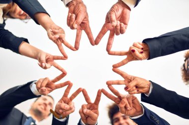 Bir grup iş adamı mutlu ve kendinden emin gülümsüyor. Yüzünde gülümsemeyle bir çemberin üzerinde durup ofiste parmaklarıyla sembol çiziyor..