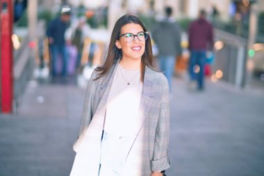 Mutlu ve kendinden emin gülümseyen genç ve güzel bir kadın. Kasaba caddesinde yüzünde gülümsemeyle dikilirken